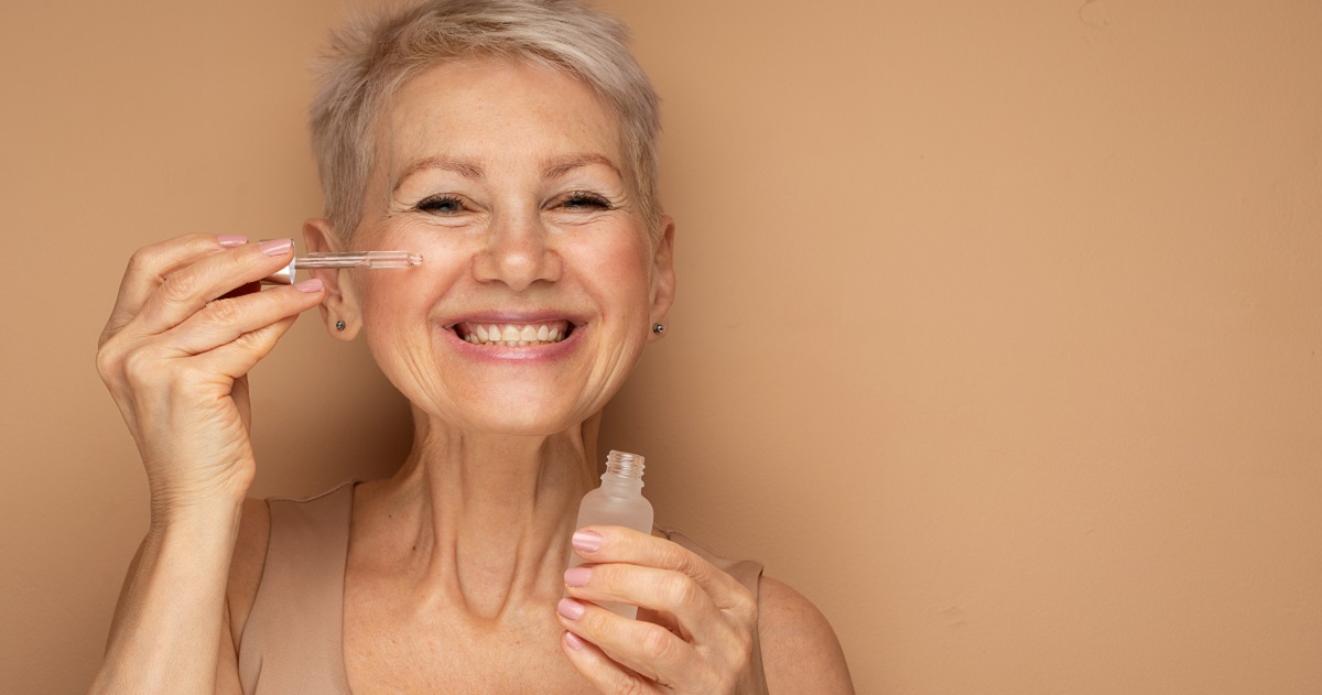 image shows a happy 50-something lady with a pippette dropper held up to her face with serum in it